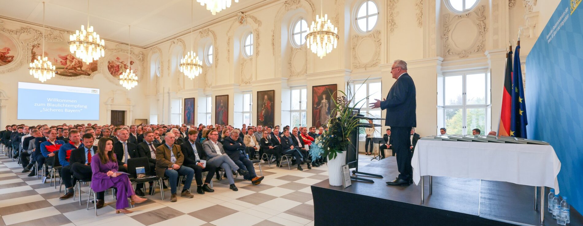 Blick in den Saal mit Publikum und Innenminister Herrmann auf Bühne am Rednerpult